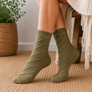 May include: A pair of mid-calf knit socks in a muted olive green color. The socks feature a distinct diagonal ribbed texture pattern that runs across the fabric from the toe up to the ribbed cuff, creating a consistent and structured appearance.