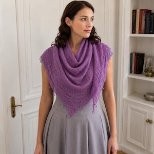May include: A triangular purple knit shawl featuring an intricate openwork lace pattern and small decorative beads along the edges, draped over a plain grey skirt. The shawl has a textured, lightweight appearance with a pointed hemline.