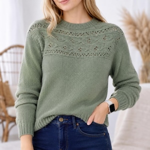 Peut inclure: Un pull à manches longues vert sauge doté d'une encolure ronde et d'un motif en tricot ajouré décoratif sur le haut de la poitrine et les épaules. Le vêtement présente des poignets et un ourlet côtelés, associé à un jean bleu foncé.