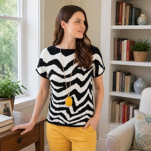 Peut inclure: Un haut en tricot à manches courtes avec un motif ondulé noir et blanc rappelant le zèbre, associé à un pantalon jaune moutarde et un long collier à chaîne dorée avec un pendentif ovale lisse de couleur jaune moutarde sur la poitrine.