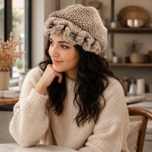 May include: A beige crochet beanie featuring a thick, braided cable knit brim and a textured, solid-stitch crown. The hat is crafted from a light tan yarn, showcasing a detailed, chunky woven pattern around the base and a simple, uniform stitch design.