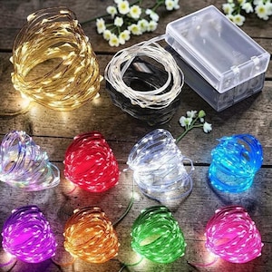 May include: A collection of ten coiled LED fairy light strands in various colors including warm white, cool white, red, blue, purple, orange, green, and pink. Each strand is connected to a clear rectangular plastic battery pack case.