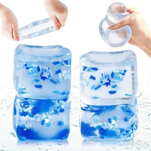 Puede incluir: Moldes transparentes para cubitos de hielo con inclusiones azules en forma de copo de nieve. La imagen muestra los moldes en uso, con manos sosteniendo el hielo flexible. Los cubitos de hielo están apilados y se ven gotas de agua.