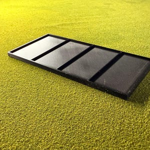 Peut inclure: Un plateau rectangulaire noir divis&eacute; en quatre compartiments &eacute;gaux. Le plateau est en mat&eacute;riau textur&eacute; et repose sur une surface textur&eacute;e jaune-vert. Les compartiments sont s&eacute;par&eacute;s par des s&eacute;parateurs sur&eacute;lev&eacute;s.