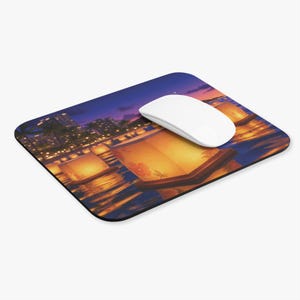 May include: A rectangular mouse pad featuring a printed scene of glowing paper lanterns floating on dark water at twilight, with a white computer mouse resting on the surface. The lanterns display floral patterns and cast warm orange light.