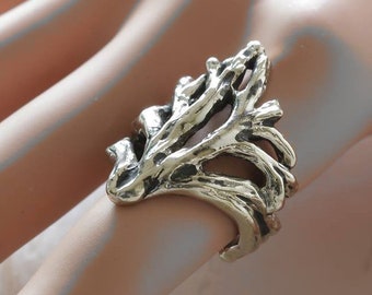 May include: A silver ring with a detailed design resembling a tree branch. The ring is worn on a model's finger.