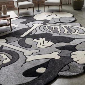 May include: A large, irregularly shaped area rug featuring a monochromatic palette of black, grey, and off-white. The design displays stylised skeletal elements, bone motifs, and cartoon-like character heads with X-shaped eyes in a layered composition.