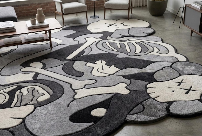 May include: A large, irregularly shaped area rug featuring a monochromatic palette of black, grey, and off-white. The design displays stylised skeletal elements, bone motifs, and cartoon-like character heads with X-shaped eyes in a layered composition.