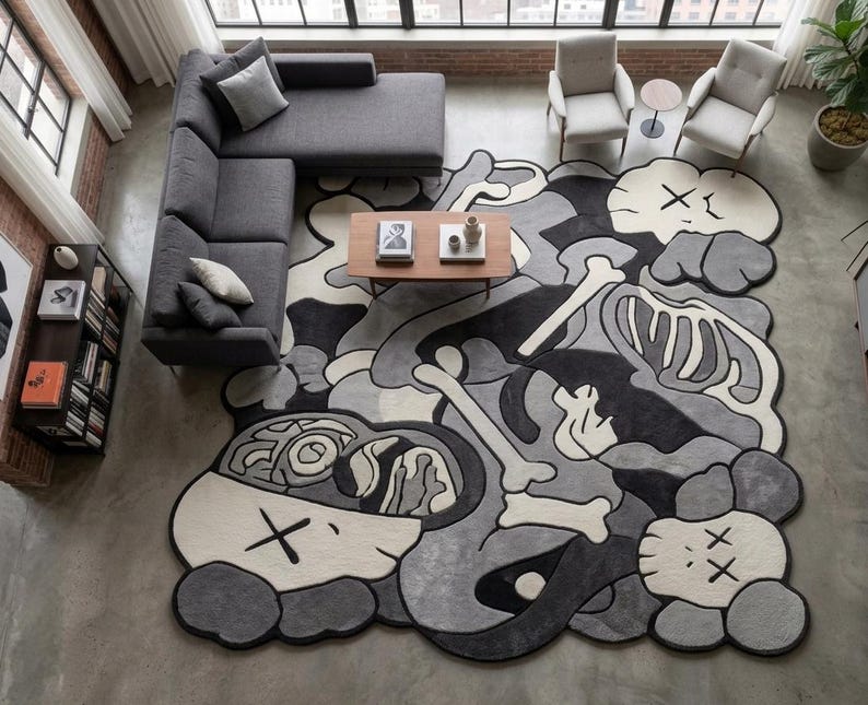 May include: A large, irregularly shaped area rug featuring a monochromatic graphic design in shades of black, grey, and off-white. The pattern displays stylised skeletal elements, abstract shapes, and multiple character heads with X-shaped eyes.