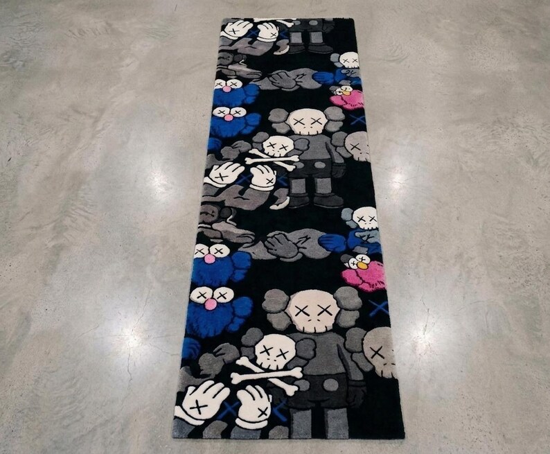 May include: A rectangular area rug featuring a black background with a repeating pattern of cartoon-style figures. The figures are depicted in shades of gray, blue, and pink, each with X-shaped eyes and white gloved hands with X markings.