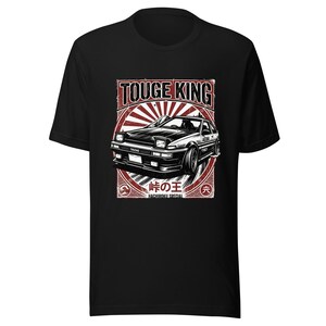 Könnte beinhalten: Schwarzes T-Shirt mit einer Grafik eines schwarz-weißen Autos und dem Text "TOUGE KING" in Rot und Weiß. Das Design enthält japanischen Text und ein Sonnenaufgangsmotiv, was einen Vintage-Look erzeugt.