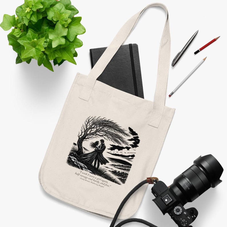 May include: A cream-coloured canvas tote bag featuring a black ink illustration of two figures embracing under a windswept tree. Below the image, the text reads: "I wish I were a girl again, half-savage and hardy, and free." - Emily Brontë, Wuthering Heights.