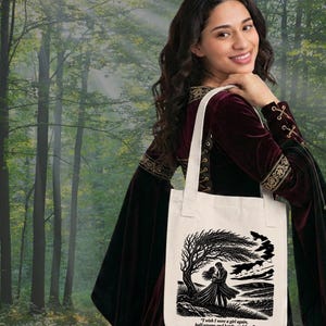 May include: A cream-colored canvas tote bag featuring a black ink illustration of two figures embracing under a windswept tree. Below the illustration, the text reads: "I wish I were a girl again, half-savage and hardy, and free." - Emily Bront&euml;, Wuthering Heights.