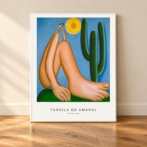 Peut inclure: Une impression d'art encadrée représentant le tableau Abaporu de Tarsila do Amaral. L'image montre une silhouette stylisée avec un pied et une main surdimensionnés assise sur un monticule vert sous un ciel bleu avec un soleil jaune et un grand cactus vert. Le texte indique TARSILA DO AMARAL ABAPORU (1928).