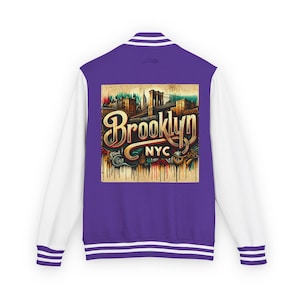 May include: A purple and white varsity jacket with the word "Brooklyn" in gold lettering on the back. The jacket has white sleeves and a purple body with white stripes on the cuffs and hem. The graphic includes the Brooklyn Bridge.