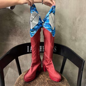 May include: A pair of red boots with blue and white camouflage print on the top of the boot shafts.