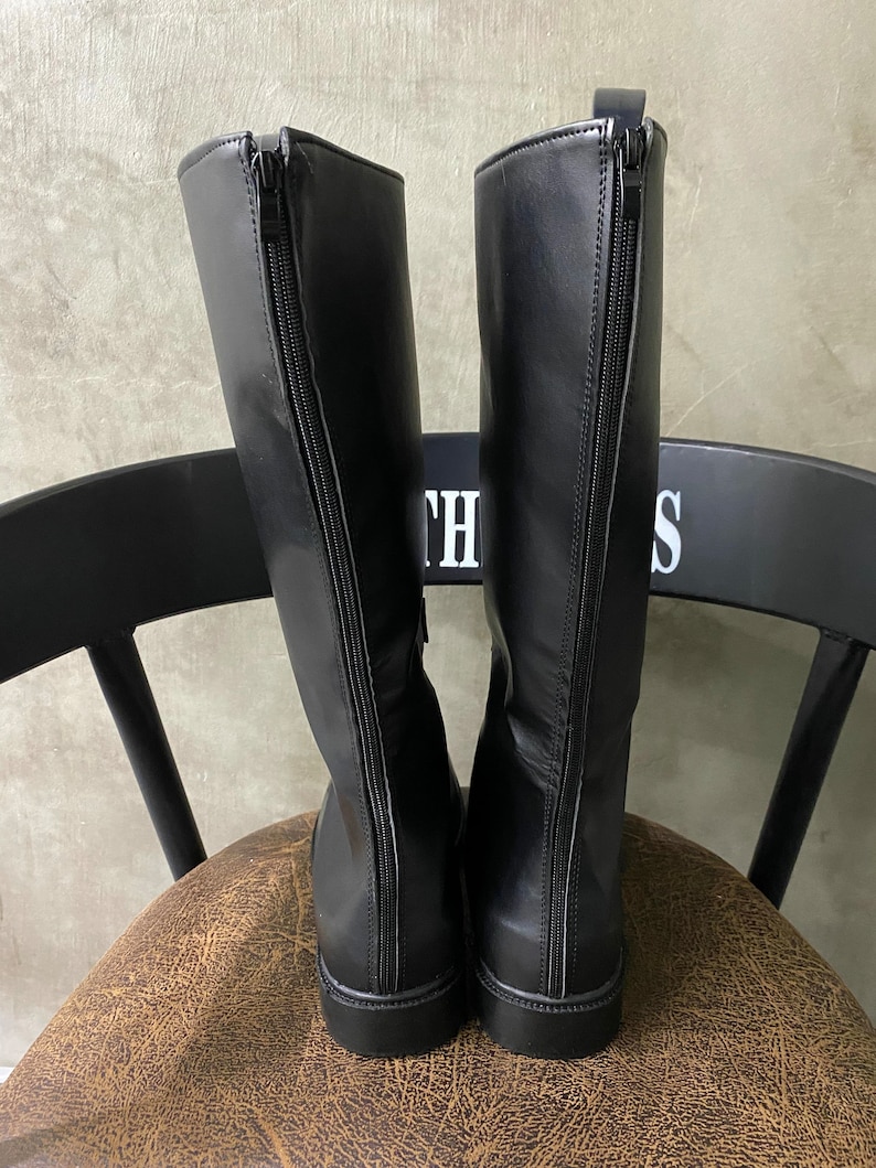 May include: A pair of black leather knee-high boots with a zipper on the back of each boot.