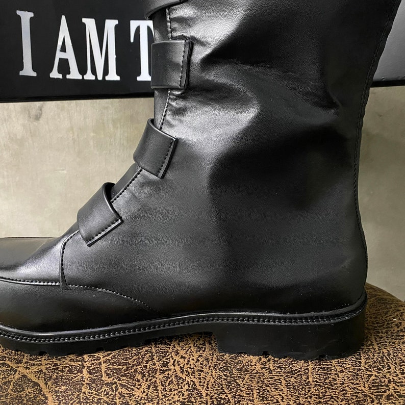 May include: Black leather boots with a buckle closure and a thick sole. The boots are made of a smooth, polished leather and have a classic, timeless design.