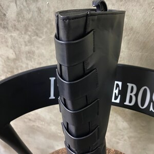 May include: Black leather knee-high boots with multiple straps and buckles.