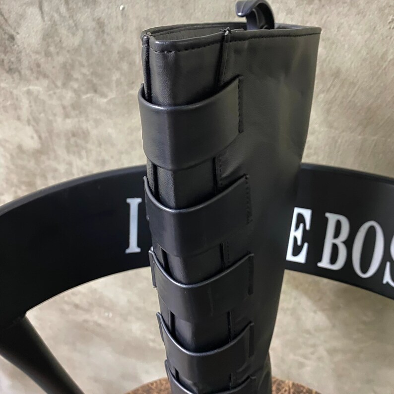 May include: Black leather knee-high boots with multiple straps and buckles.