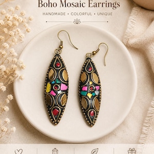 Op de afbeelding: Boho mozaïek oorbellen met een uniek design. De oorbellen hebben een donkere basis met kleurrijke mozaïek accenten, goudkleurige metalen details en een haaksluiting. De tekst op de afbeelding luidt "HANDMADE • COLORFUL • UNIQUE".