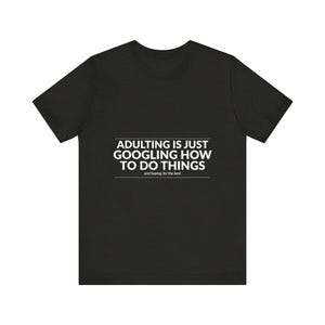 Puede incluir: Camiseta negra con el texto blanco "ADULTING IS JUST GOOGLING HOW TO DO THINGS" y la frase "and hoping for the best". Una prenda casual.