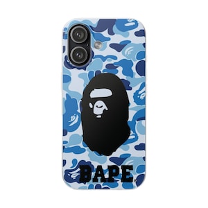 Puede incluir: Funda de teléfono con un patrón de camuflaje azul y un gráfico negro de una cabeza de gorila. La palabra "BAPE" está impresa en negro en la parte inferior. La funda tiene un borde transparente y dos lentes de cámara.
