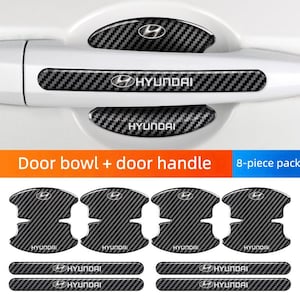 May include: A set of black and gray carbon fiber-style door handle and bowl protectors for a Hyundai vehicle. The set includes pieces for the door handles and the door bowls, with the Hyundai logo and text. The text "Door bowl + door handle" is also visible.