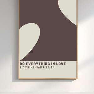 May include: A framed art print with a minimalist design. The artwork features a brown background with two off-white, curved shapes. The bottom section is a light beige with the text "DO EVERYTHING IN LOVE" and "1 CORINTHIANS 16:14".