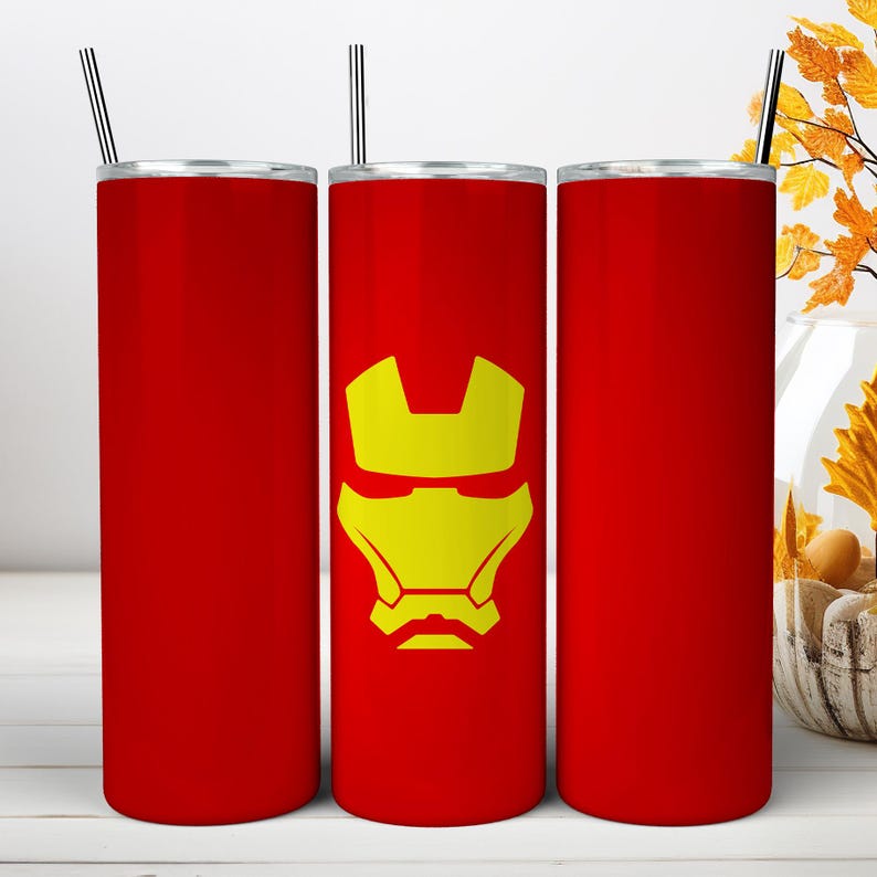 May include: Three tall, cylindrical red tumblers with silver metal straws. The center tumbler features a yellow graphic of a stylized helmet mask. Each tumbler has a flat lid and a smooth, solid red finish, providing a consistent look across all items.