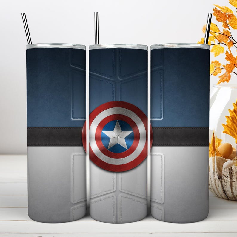 May include: A cylindrical stainless steel tumbler featuring a graphic design inspired by a superhero shield. The design includes a central red, white, and blue star emblem, a dark blue upper section, a grey lower section, and a black horizontal band.