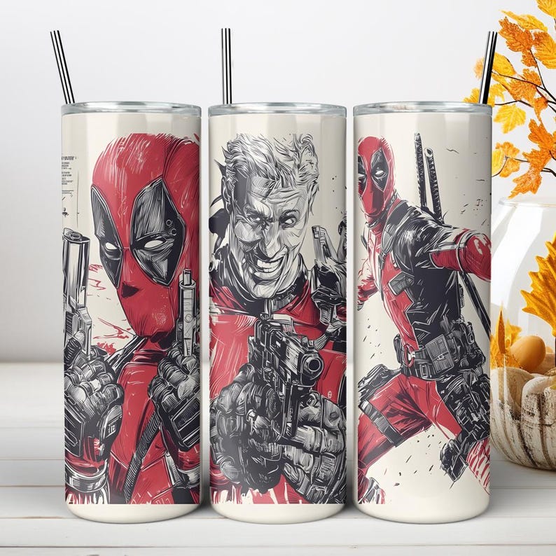 May include: A cylindrical stainless steel tumbler featuring a graphic illustration of the character Deadpool in red and black. The design includes a masked portrait, an unmasked face, and a full-body action pose, each holding a handgun.