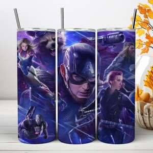 May include: A cylindrical stainless steel tumbler featuring a wrap-around graphic print of Marvel superheroes including Captain America, Black Widow, Thor, Rocket Raccoon, Captain Marvel, and War Machine against a dark blue cosmic background.