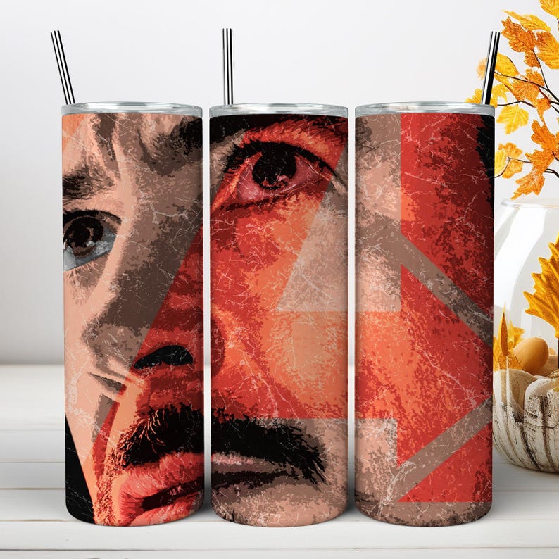 May include: Three cylindrical tumblers with metal straws, each featuring a distressed, graphic print of a person's face in shades of red, orange, and black. The design includes a large, faded number four overlaid across the surface of the cups.