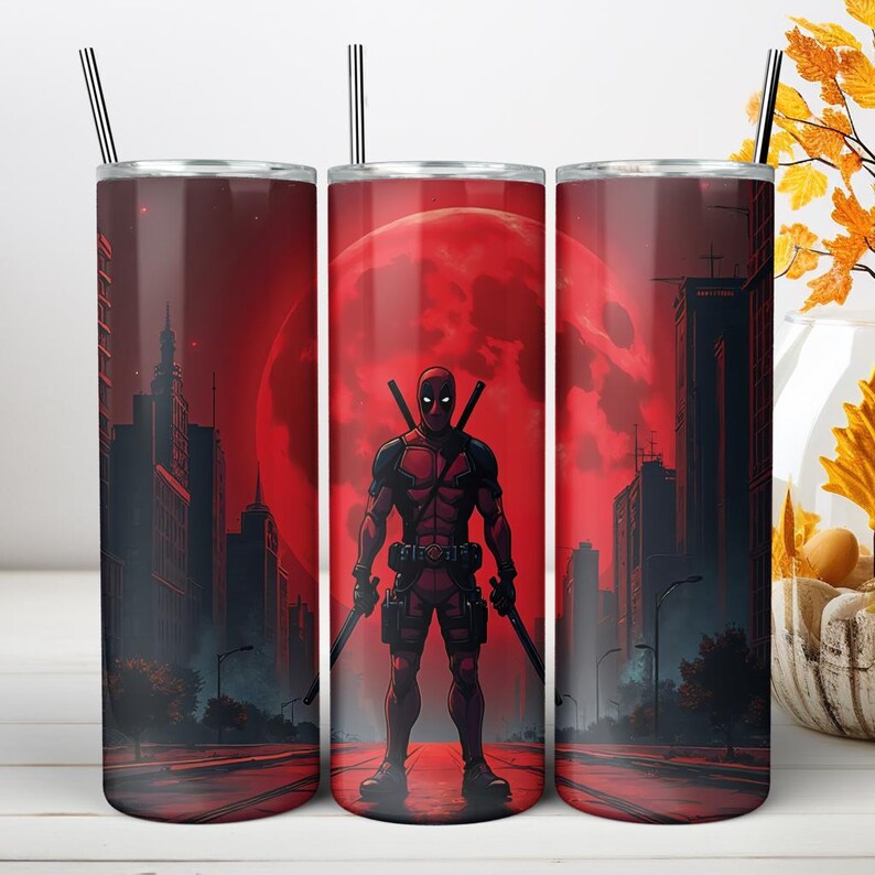 May include: A cylindrical tumbler featuring a red and black graphic print of a masked character with two swords standing in a city street under a large red moon. The tumbler includes a thin metal straw extending from the top lid opening.