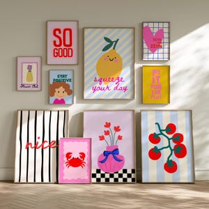 Könnte beinhalten: Eine Galeriewand mit zehn gerahmten Kunstdrucken, die bunte Illustrationen eines Zitronenmotivs mit dem Text squeeze your day, einen Krebs, Tomaten, Blumen in einer Vase, ein Herz sowie motivierende Sprüche wie so good und stay positive zeigen.