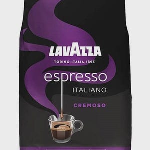 May include: A black bag of Lavazza Espresso Italiano Cremoso coffee beans. The packaging features a purple graphic of steam rising from a glass cup of espresso. Text includes Lavazza, Torino, Italia, 1895, espresso, Italiano, Cremoso, and 1000g.