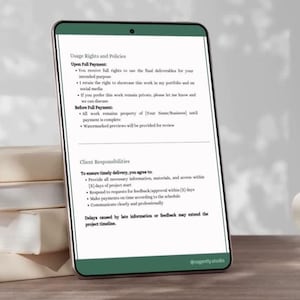 Op de afbeelding: Een smartphone toont een document met informatie over gebruiksrechten en verantwoordelijkheden van de klant. Het staat naast een stapel boeken en een witte mok op een houten oppervlak. Het document bevat de tekst "@prosperity.studio".