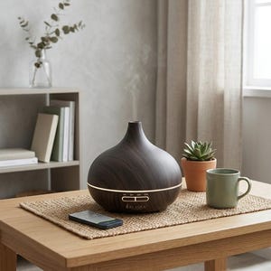 May include: A dark wood grain finish essential oil diffuser with a rounded base and a narrow neck, emitting a thin stream of mist. The device features a horizontal light strip, timer settings labeled 1H, 3H, 6H, ON, and the brand name ALASKA.