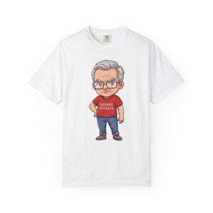 May include: A white short-sleeved t-shirt featuring a cartoon illustration of an older person with grey hair and glasses, wearing a red shirt with the text GRUMPY GRANDPA printed in white, blue jeans, and colourful trainers on a plain white background.