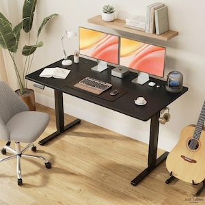 May include: A black height-adjustable desk with two computer monitors, a keyboard, and a mouse. A small desk lamp, a cup of coffee, and headphones are also on the desk. A guitar leans against the desk.