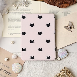 May include: A pink tablet case featuring a repeating pattern of black cat silhouettes. The case is rectangular and appears to be made of a smooth material. The design is simple and playful, suitable for cat lovers.