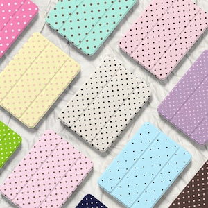 Può includere: Un assortimento di custodie per tablet dai colori pastello, ciascuna ornata da un motivo a pois. Le custodie sono in vari colori, tra cui rosa, giallo, verde, blu e viola. Sono disposte su uno sfondo bianco.
