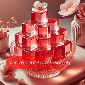 May include: A pyramid of translucent, red-tinted cubes sits in a decorative glass bowl. The cubes are topped with a white flower. The image includes a small vase with pink flowers and the text "for Weight Loss & Satiety" in a red banner.