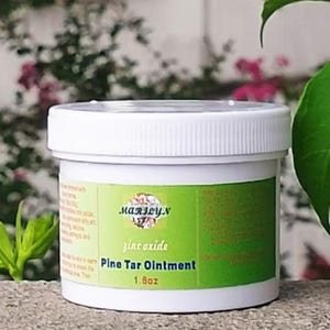 May include: A white plastic jar with a green label featuring the text Marilyn, Zinc oxide, Pine Tar Ointment, and 1.8oz. The container has a ribbed screw-top lid and contains a topical ointment, with the product weight clearly printed on the label.