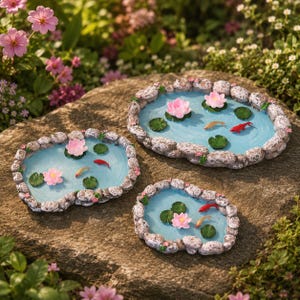 Könnte beinhalten: Drei Miniatur-Gartenteiche mit hellblauem Wassereffekt, umgeben von Steinrändern. Jeder Teich zeigt rosa Lotusblüten, grüne Seerosenblätter und kleine, bunte Fische. Die Teiche sind auf einer großen, natürlichen Steinoberfläche platziert, umgeben von Grün.