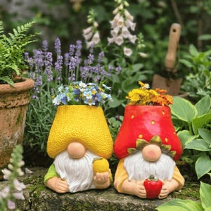 Könnte beinhalten: Zwei skurrile Zwergen-Pflanzgefäße, eines gelb und eines rot, gefüllt mit bunten Blumen. Der gelbe Zwerg hält eine Zitrone, der rote Zwerg eine Erdbeere. Diese charmanten Gartendekorationen verleihen jedem Außenbereich einen Hauch von Fantasie.