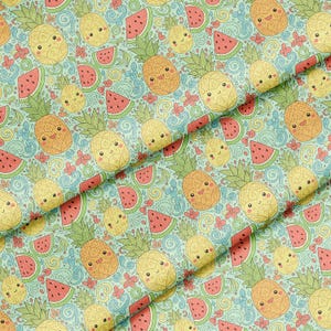 Op de afbeelding: Een lichtgroene stof met een herhalend patroon van lachende cartoonananassen, watermeloenpartjes en kleine roze bloemen, allemaal verbonden door blauwe, wervelende lijntekeningen over het gehele oppervlak van het materiaal.