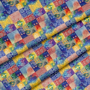 Op de afbeelding: Een kleurrijke patchworkstof met een verscheidenheid aan patronen en kleuren. Het ontwerp bevat vierkanten in blauw, geel, rood en groen met wervelingen, cirkels en andere geometrische vormen. De stof is gevouwen en toont de textuur en details.
