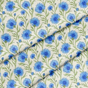Pode incluir: Um tecido com um padrão botânico repetitivo de centáureas azul-brilhante com caules e folhas verdes sobre um fundo creme. O design inclui múltiplas cabeças de flores em vários estágios de floração.